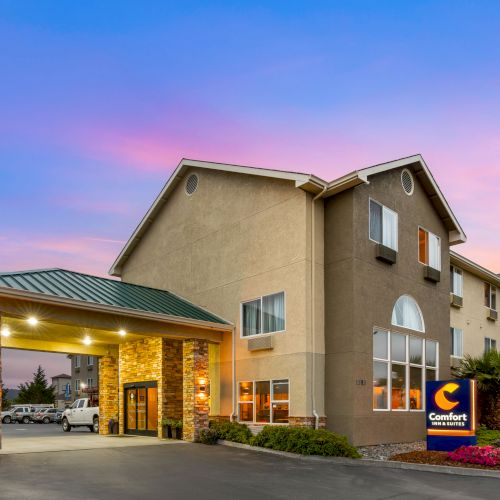 Image shows an exterior of a Comfort Inn hotel at sunset. The building has a covered entrance, visible sign, and well-maintained landscape ending the sentence.